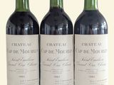 three bottles of red wine are lined up on a white surface