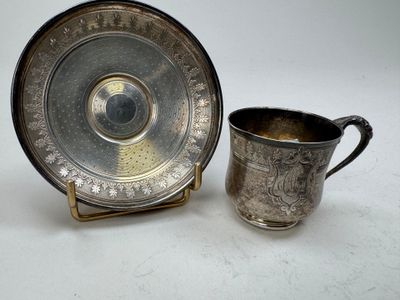 a silver cup and saucer sitting next to each other