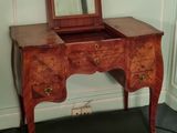a small wooden vanity with a mirror on top of it