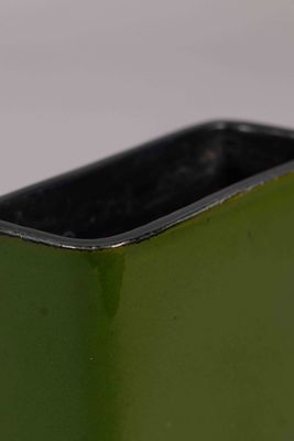 un vase vert bordé de noir posé sur une table