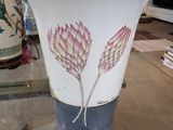 un vase posé sur une table en verre, avec un autre vase à l'arrière-plan