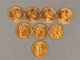 six gold sovereigns of various sizes and shapes on a gray surface