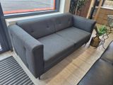 a grey couch sitting in a living room next to a window