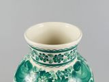a green and white vase sitting on a table