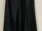 a black blazer jacket hanging on a white brick wall