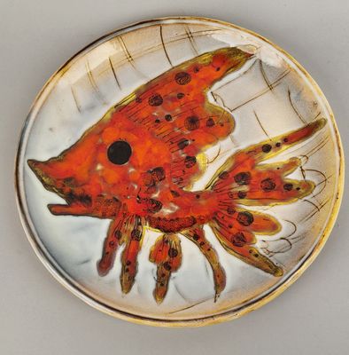 une assiette en verre sur laquelle est posé un poisson, posée sur une table