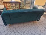 green couch sitting on a brick patio next to a table