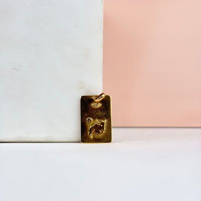 un pendentif plaqué or représentant un chien assis sur un bloc de marbre
