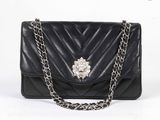 sac à main en cuir noir avec une bandoulière en chaîne et une broche en forme de fleur