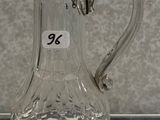a clear glass pitcher with a handle on a table