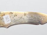 a silver knife with a tag on it on a white surface