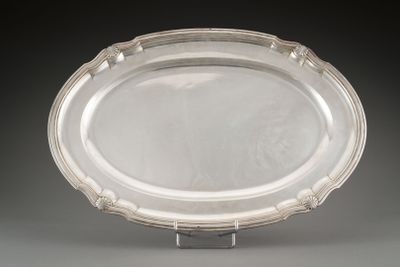 an oval silver tray with a raised edge on a stand