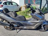 a silver motorcycle parked in a parking lot next to a white car