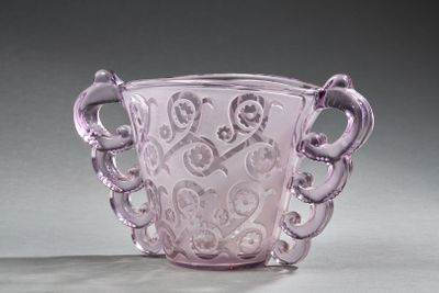 un vase en verre violet muni d'une anse, posé sur une table