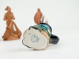 two figurines sitting next to each other on a white surface