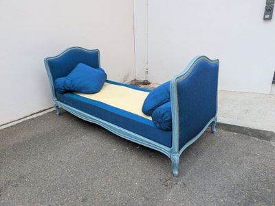 a blue day bed with pillows on it in a corner