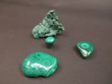 trois morceaux de jade vert sont posés sur une table, à côté de quelques pierres