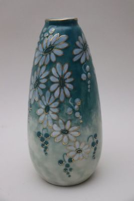 un vase bleu orné de fleurs blanches, posé sur une surface blanche