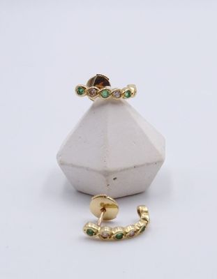 Gros plan sur une bague en or ornée de pierres vertes