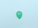 a green emerald gems on a white surface