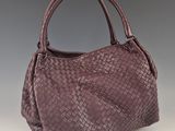 un sac à main en cuir tressé violet sur fond gris