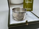 a silver cup sitting in a box next to a bottle of wine