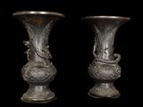 two silver vases sitting side by side on a black background