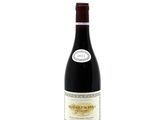 the bottle of red wine is sitting on a white surface