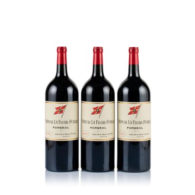 trois bouteilles de vin rouge posées l'une à côté de l'autre sur une surface blanche