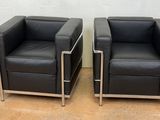 pair of black leather lounge chairs with chrome legs