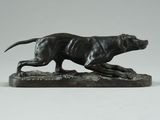 a bronze statue of a dog running on a rock