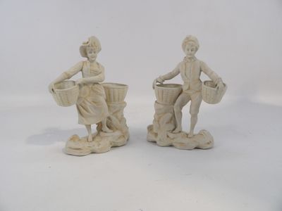 deux figurines représentant un homme et une femme portant des paniers sur la tête