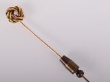 a close up of a gold pin with a knot on it