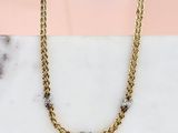 une photo d'un collier à chaîne en or posé sur une surface en marbre