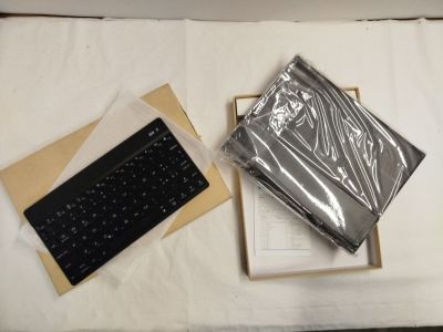un ordinateur portable et un clavier dans une boîte posée sur un lit