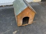 une petite niche en bois avec un toit, posée à même le sol
