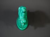 green glass figurine of a frog sitting on top of a black surface