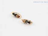 a pair of black and gold earrings on a white surface