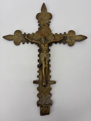 un gros plan d'une croix accrochée à un mur, sur laquelle se trouve une personne