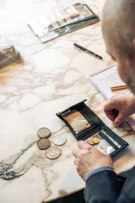 un homme assis à une table, avec un portefeuille et des pièces de monnaie devant lui