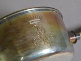 a silver pot with a crown on it sitting on a table
