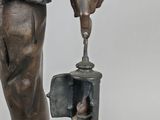 bronze statue of a man holding a lamp and a bird in his hand