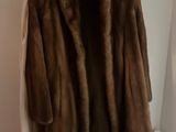 brown fur coat hanging on a hanger in a white room