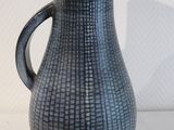 un vase noir muni d'une anse, posé sur une table