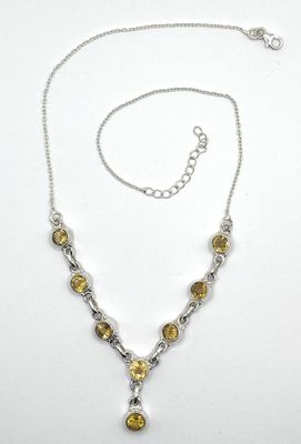 a close up of a necklace on a white surface with a chain