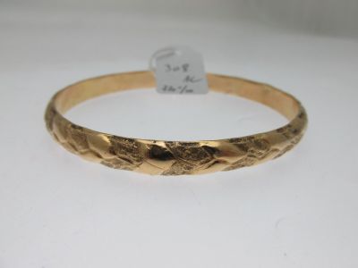 gros plan d'un bracelet en or sur une surface blanche