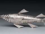 silver fish figurine on grey background with black background