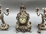 three candles and a clock sitting on a table