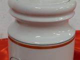 a white jar with a lid on a red cloth