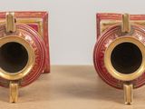 two red and gold vases sitting on a table